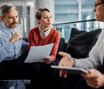 Mid adult couple and their financial advisor discussing about pa Servicio de asesoramiento en herencias